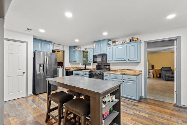 201 S Caney St, Dodd City, TX 75438 - kitchen with black appliances, blue cabinets, light wood-type flooring, a sink, and recessed lighting