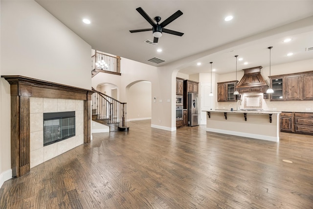 6809 Gallatin St, Mckinney, TX 75070 - unfurnished living room with ceiling fan, a fireplace, arched walkways, stairway, and dark wood finished floors