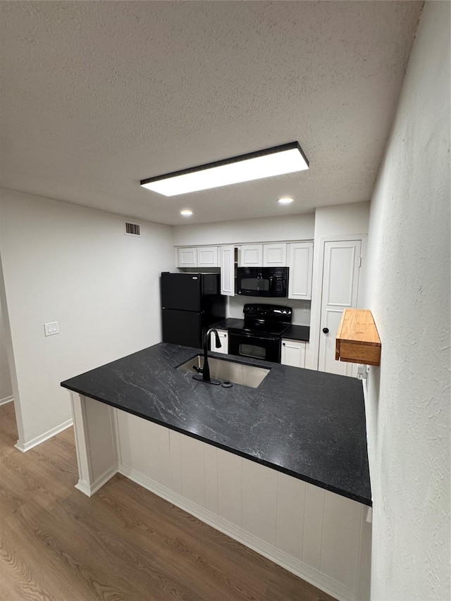 4859 Cedar Springs Rd Unit 150, Dallas, TX 75219 - kitchen with black appliances, a sink, a textured ceiling, dark wood-style floors, and white cabinetry