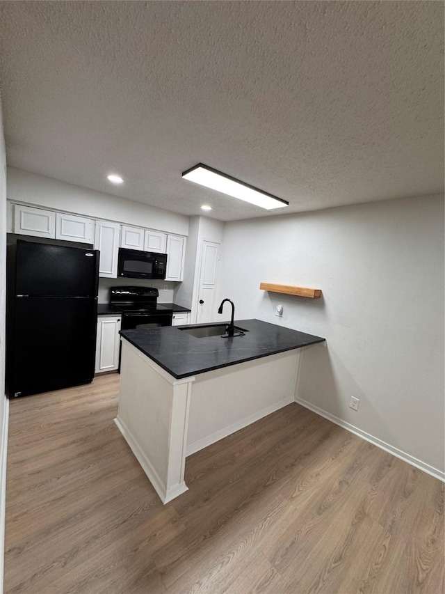 4859 Cedar Springs Rd Unit 150, Dallas, TX 75219 - kitchen featuring black appliances, a sink, a peninsula, a textured ceiling, and dark countertops