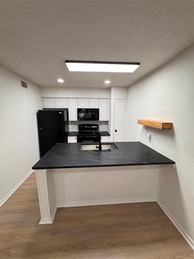 4859 Cedar Springs Rd Unit 150, Dallas, TX 75219 - kitchen with black appliances, a sink, white cabinets, wood finished floors, and recessed lighting
