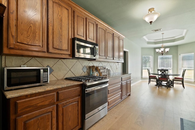 208 Burtonwood Cir, Ovilla, TX 75154 - kitchen featuring stainless steel appliances, tasteful backsplash, light wood finished floors, a chandelier, and brown cabinets