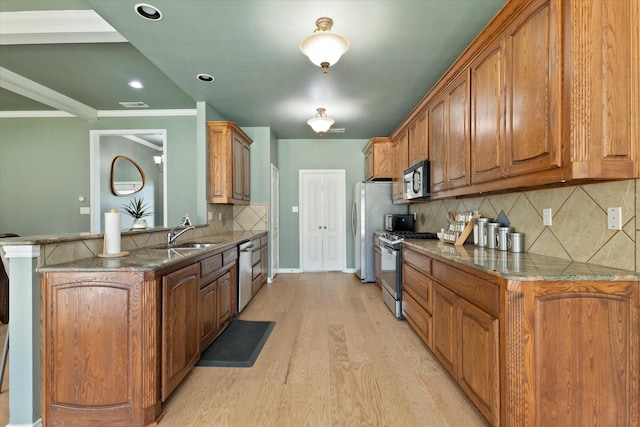 208 Burtonwood Cir, Ovilla, TX 75154 - kitchen featuring appliances with stainless steel finishes, a sink, light wood finished floors, brown cabinets, and backsplash