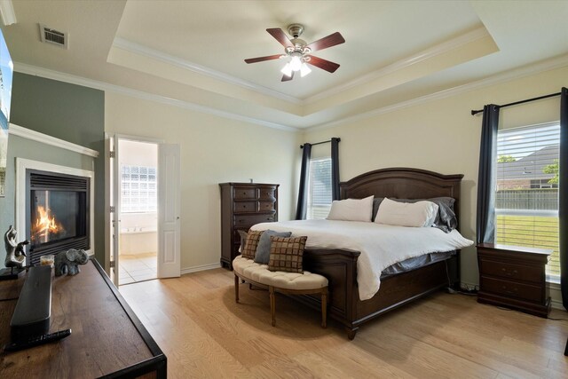 208 Burtonwood Cir, Ovilla, TX 75154 - bedroom with a raised ceiling, light wood finished floors, multiple windows, a glass covered fireplace, and crown molding