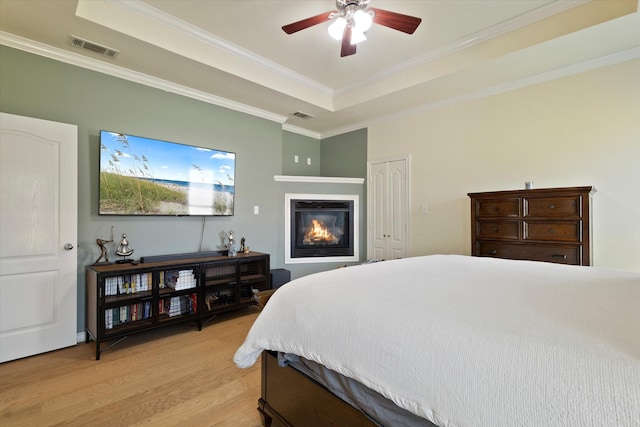 208 Burtonwood Cir, Ovilla, TX 75154 - bedroom with a raised ceiling, light wood-style floors, ornamental molding, a glass covered fireplace, and a ceiling fan