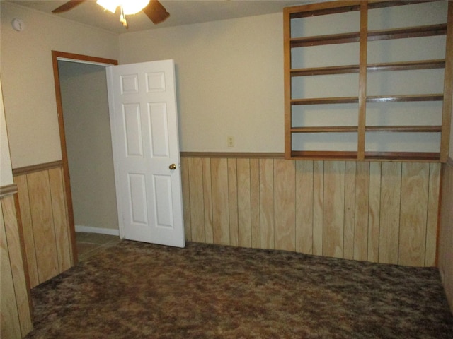 261 Airport Rd, Emory, TX 75440 - empty room featuring ceiling fan, dark carpet, wood walls, wainscoting, and a smoke detector