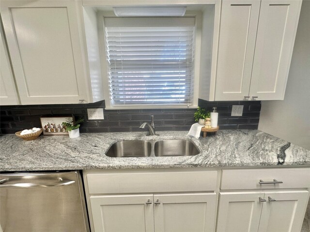 1902 College St, Gainesville, TX 76240 - kitchen featuring dishwasher, a sink, backsplash, and white cabinetry