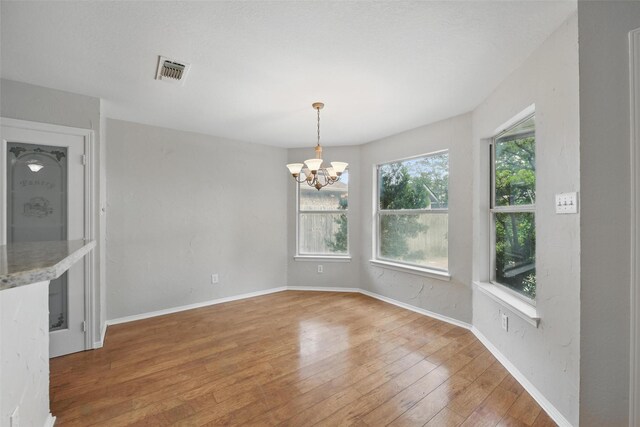 9228 Winslow Ct, North Richland Hills, TX 76182 - unfurnished dining area with a chandelier, wood-type flooring, and baseboards