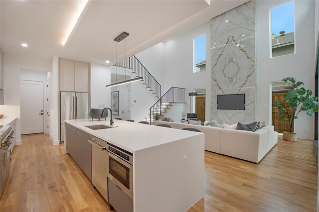 8506 Craighill Ave, Dallas, TX 75209 - kitchen featuring modern cabinets, a sink, a high end fireplace, pendant lighting, and light wood-type flooring