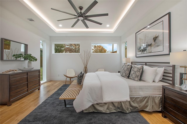 8506 Craighill Ave, Dallas, TX 75209 - bedroom featuring light wood-style flooring, a raised ceiling, and a ceiling fan