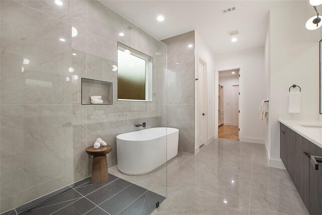 8506 Craighill Ave, Dallas, TX 75209 - bathroom featuring tile walls, vanity, a soaking tub, marble tiled floors, and baseboards