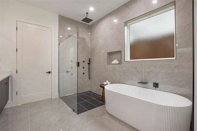 8506 Craighill Ave, Dallas, TX 75209 - bathroom featuring walk in shower, tile walls, a soaking tub, vanity, and marble finish flooring