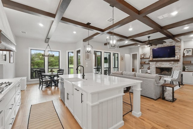 1020 Sky Rd, Weatherford, TX 76087 - kitchen with a sink, a fireplace, a ceiling fan, light wood finished floors, and beam ceiling