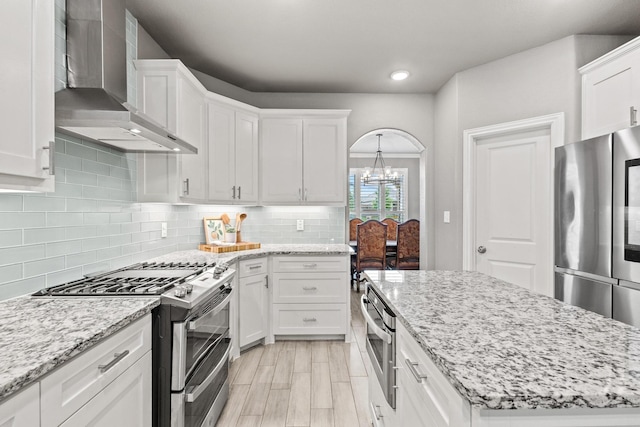 3723 Parkwood Ln, Denison, TX 75020 - kitchen featuring wall chimney exhaust hood, appliances with stainless steel finishes, a chandelier, white cabinetry, and recessed lighting