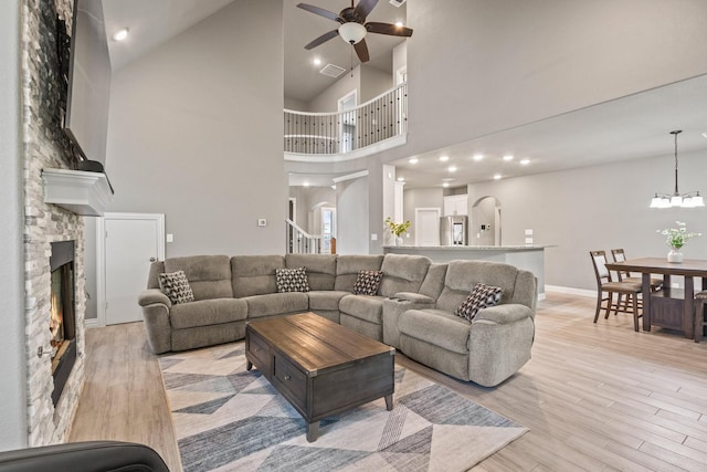 3723 Parkwood Ln, Denison, TX 75020 - living room featuring a ceiling fan, a stone fireplace, light wood-style flooring, high vaulted ceiling, and a chandelier