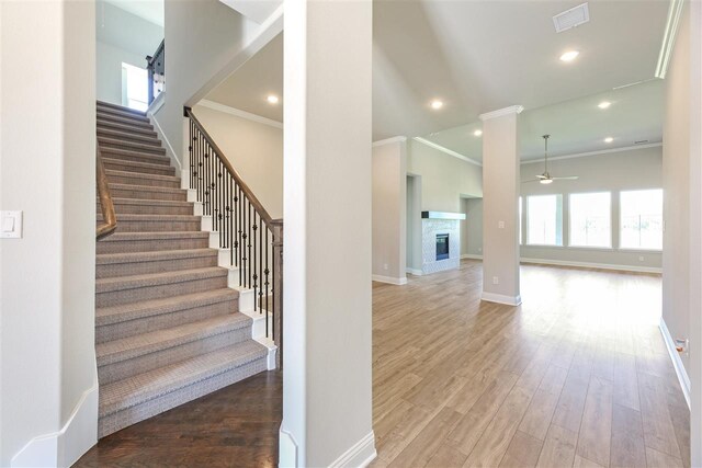 2207 Morris St, Rockwall, TX 75087 - staircase featuring healthy amount of natural light, a ceiling fan, ornamental molding, a glass covered fireplace, and wood finished floors