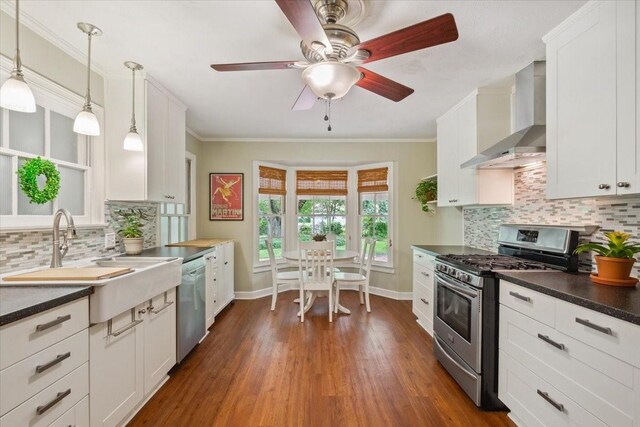 3808 Huaco Ln, Waco, TX 76710 - kitchen featuring appliances with stainless steel finishes, wall chimney exhaust hood, a sink, dark countertops, and white cabinets