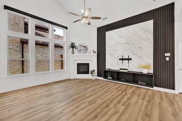 8141 Meadow Valley Dr, Mckinney, TX 75071 - unfurnished living room with a high ceiling, wood finished floors, ceiling fan, a fireplace, and baseboards