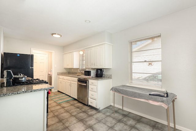 2517 Blanton St, Dallas, TX 75227 - kitchen with freestanding refrigerator, stainless steel dishwasher, baseboards, white cabinets, and light stone counters