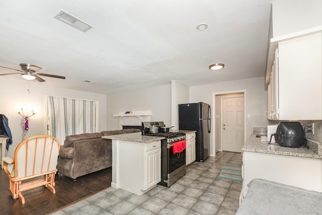 2517 Blanton St, Dallas, TX 75227 - kitchen with stainless steel range with gas cooktop, freestanding refrigerator, open floor plan, white cabinetry, and ceiling fan