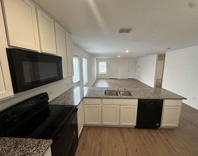 1408 Silver Oak Ln, Fort Worth, TX 76140 - kitchen featuring black appliances, a sink, a peninsula, light wood finished floors, and white cabinetry