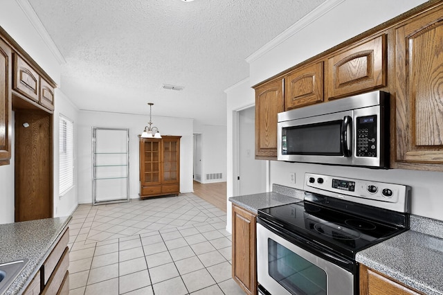 902 Church St, Sanger, TX 76266 - kitchen featuring appliances with stainless steel finishes, light tile patterned flooring, brown cabinetry, a textured ceiling, and pendant lighting