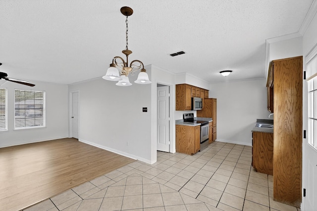 902 Church St, Sanger, TX 76266 - kitchen with stainless steel appliances, brown cabinetry, a chandelier, a ceiling fan, and light tile patterned flooring