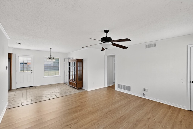 902 Church St, Sanger, TX 76266 - unfurnished living room with light wood-type flooring, a textured ceiling, a ceiling fan, and a chandelier