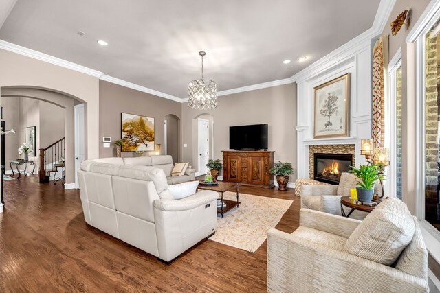 7363 Calla Lilly Ln, Frisco, TX 75034 - living room featuring arched walkways, dark wood-style floors, crown molding, a fireplace, and recessed lighting