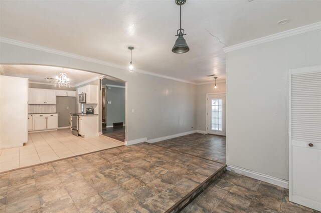 133 SE Newton Dr, Burleson, TX 76028 - unfurnished living room featuring arched walkways, a chandelier, ornamental molding, stone finish floors, and baseboards