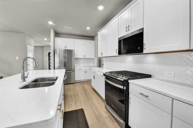 9100 Cacti Ct, Fort Worth, TX 76036 - kitchen with stainless steel appliances, a sink, light wood-style flooring, backsplash, and white cabinets