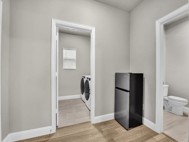 9100 Cacti Ct, Fort Worth, TX 76036 - laundry room featuring washer and dryer, light wood-type flooring, and baseboards