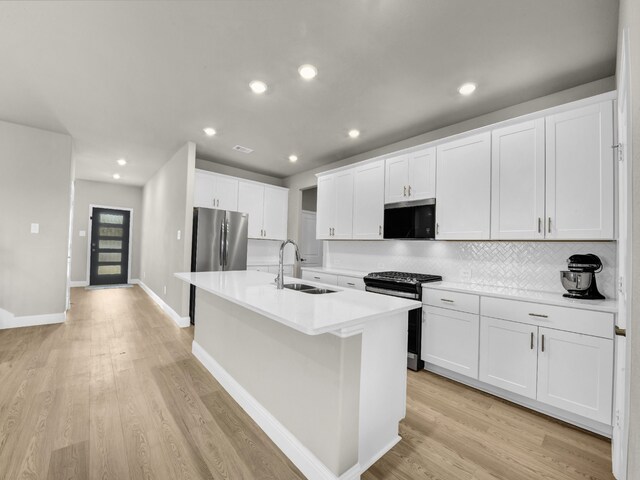 9100 Cacti Ct, Fort Worth, TX 76036 - kitchen with freestanding refrigerator, a sink, gas stove, tasteful backsplash, and a center island with sink