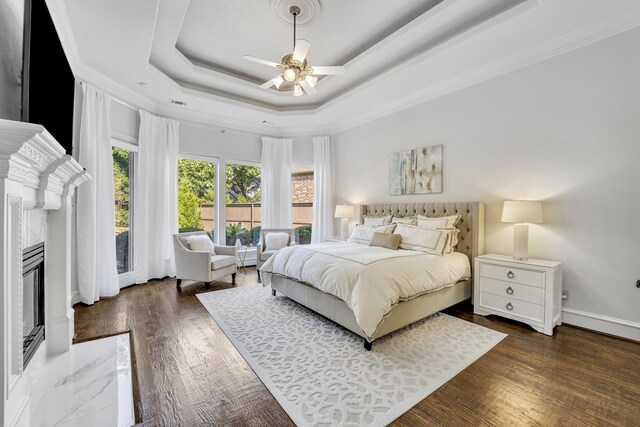 7209 Braemar Ter, Colleyville, TX 76034 - bedroom featuring a fireplace, a tray ceiling, ornamental molding, wood finished floors, and a ceiling fan