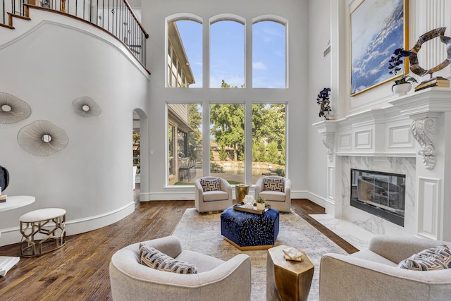 7209 Braemar Ter, Colleyville, TX 76034 - living room featuring a high ceiling, a fireplace, wood finished floors, baseboards, and arched walkways