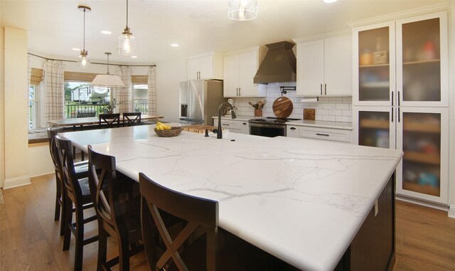 13417 Hickory Creek Dr, Haslet, TX 76052 - kitchen featuring custom exhaust hood, appliances with stainless steel finishes, a spacious island, recessed lighting, and wood finished floors
