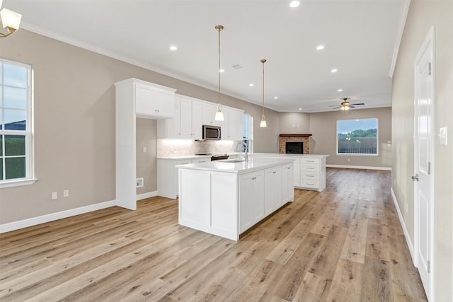 5128 Country Club Dr, Granbury, TX 76049 - kitchen with stainless steel microwave, open floor plan, a fireplace, ceiling fan, and white cabinetry