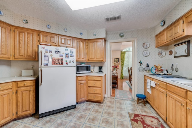 1412 Hyde Park Ln, Arlington, TX 76015 - kitchen with freestanding refrigerator, stainless steel microwave, wallpapered walls, light countertops, and a textured ceiling