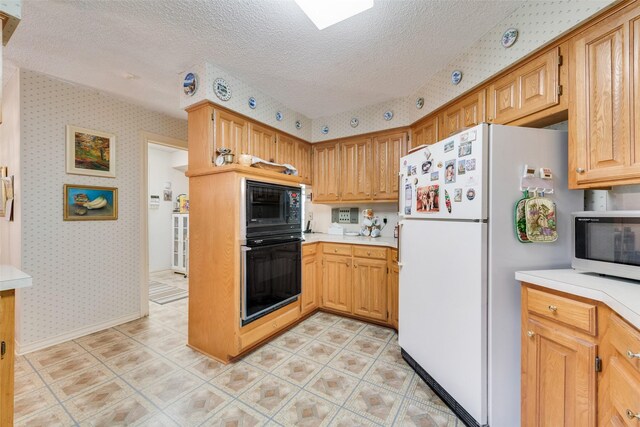 1412 Hyde Park Ln, Arlington, TX 76015 - kitchen featuring black appliances, wallpapered walls, a textured ceiling, and light countertops