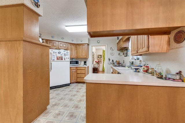 1412 Hyde Park Ln, Arlington, TX 76015 - kitchen with freestanding refrigerator, stainless steel microwave, a peninsula, light floors, and light countertops
