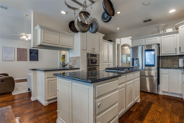 9808 Capilano Dr, Plano, TX 75025 - kitchen with appliances with stainless steel finishes, arched walkways, a kitchen island, backsplash, and ceiling fan