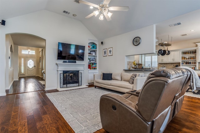 9808 Capilano Dr, Plano, TX 75025 - living room featuring arched walkways, ceiling fan, dark wood-style flooring, vaulted ceiling, and built in shelves