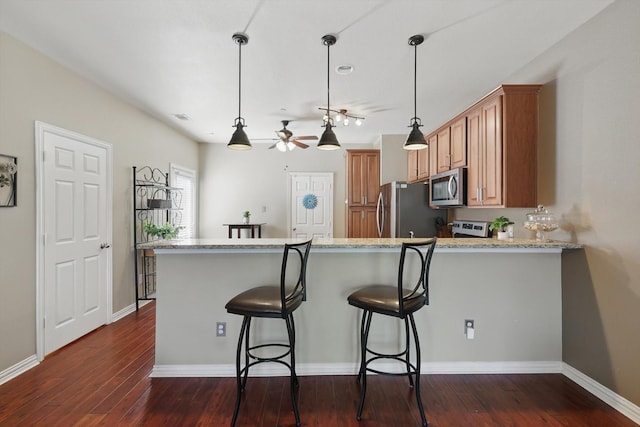 575 S Virginia Hills Dr Unit 3702, Mckinney, TX 75070 - kitchen with stainless steel appliances, dark wood-type flooring, light stone countertops, a peninsula, and a kitchen breakfast bar