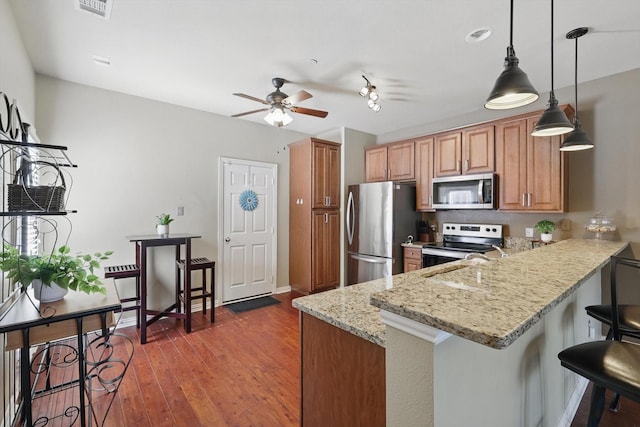 575 S Virginia Hills Dr Unit 3702, Mckinney, TX 75070 - kitchen featuring stainless steel appliances, ceiling fan, wood-type flooring, light stone countertops, and a breakfast bar