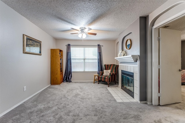 1017 Lake Trail Dr, Little Elm, TX 75068 - living area featuring carpet floors, a ceiling fan, a tiled fireplace, a textured ceiling, and baseboards