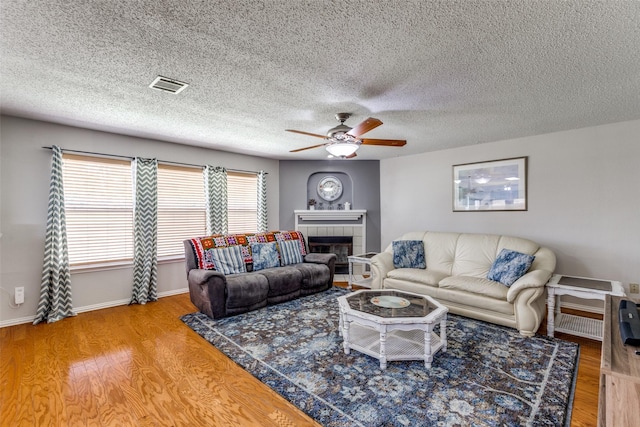 1017 Lake Trail Dr, Little Elm, TX 75068 - living room with a ceiling fan, wood finished floors, a tile fireplace, baseboards, and a textured ceiling