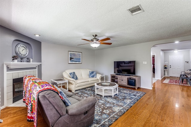 1017 Lake Trail Dr, Little Elm, TX 75068 - living area with a textured ceiling, a ceiling fan, arched walkways, a fireplace, and wood finished floors