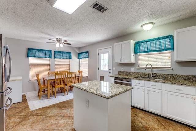 1017 Lake Trail Dr, Little Elm, TX 75068 - kitchen with a sink, a ceiling fan, a kitchen island, white cabinets, and appliances with stainless steel finishes