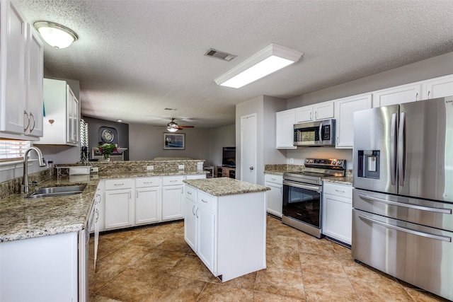 1017 Lake Trail Dr, Little Elm, TX 75068 - kitchen with appliances with stainless steel finishes, a sink, a peninsula, white cabinetry, and a textured ceiling