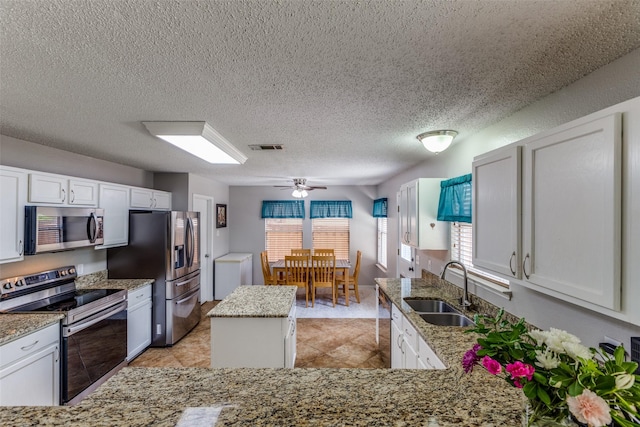 1017 Lake Trail Dr, Little Elm, TX 75068 - kitchen with appliances with stainless steel finishes, a sink, light stone counters, a kitchen island, and a textured ceiling